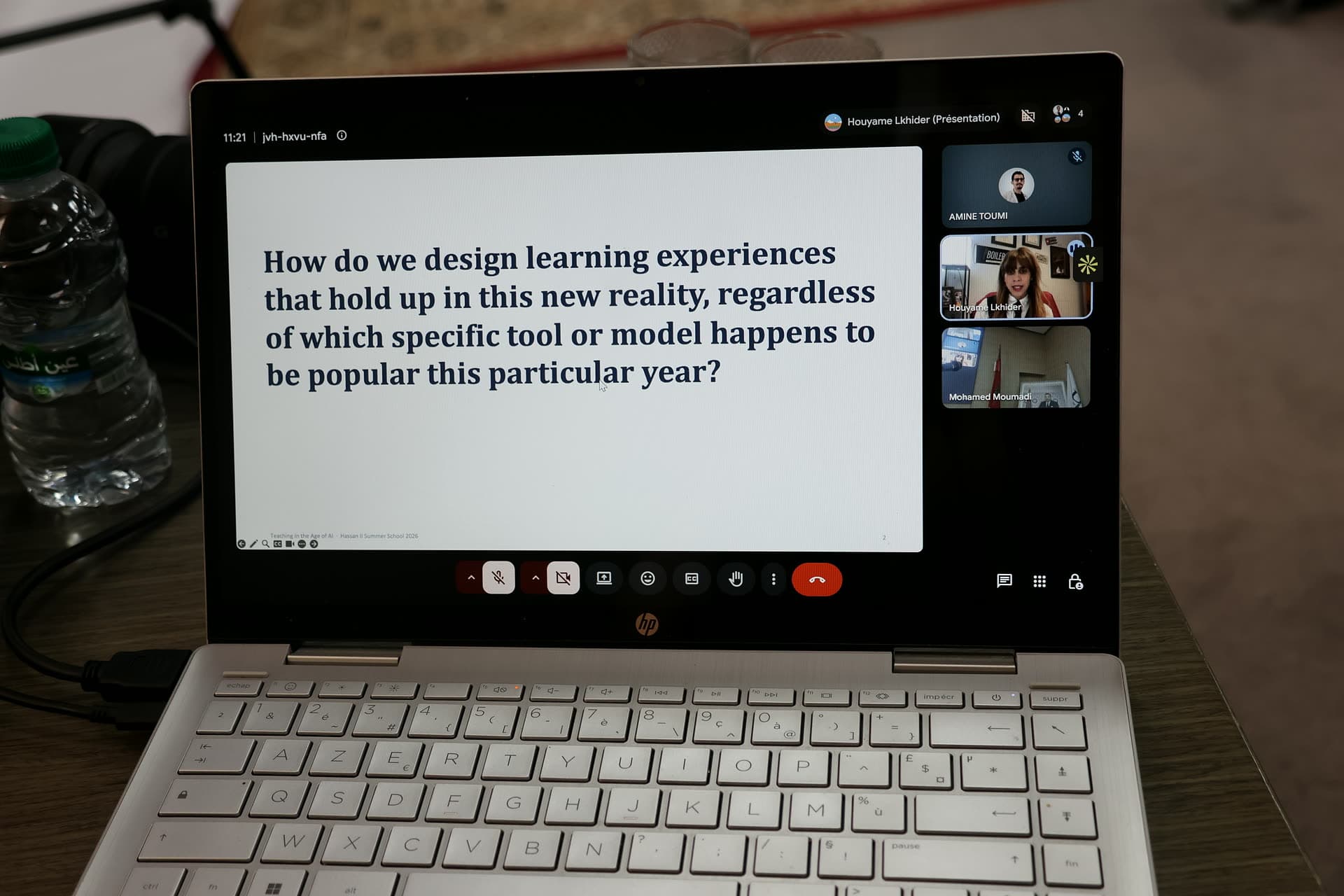 Close-up of a laptop running the live video call, a question slide shared on screen with speakers in the side panel.