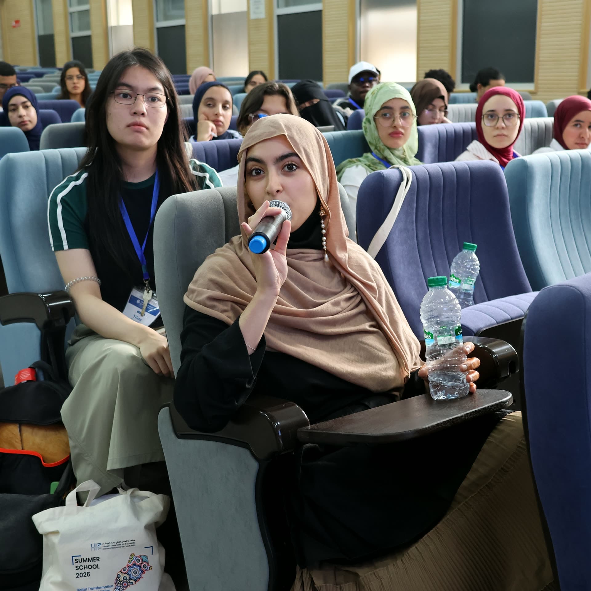 A participant speaking into the microphone from her seat during the Q&A.