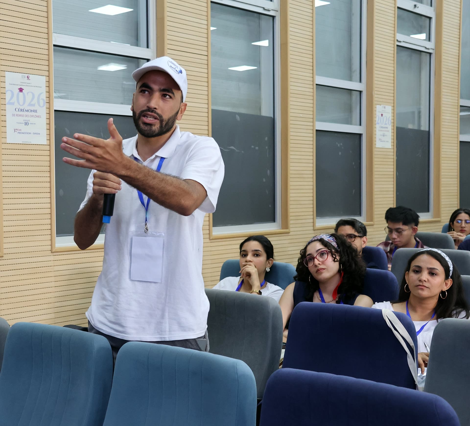 A participant standing and gesturing expressively while asking a question.