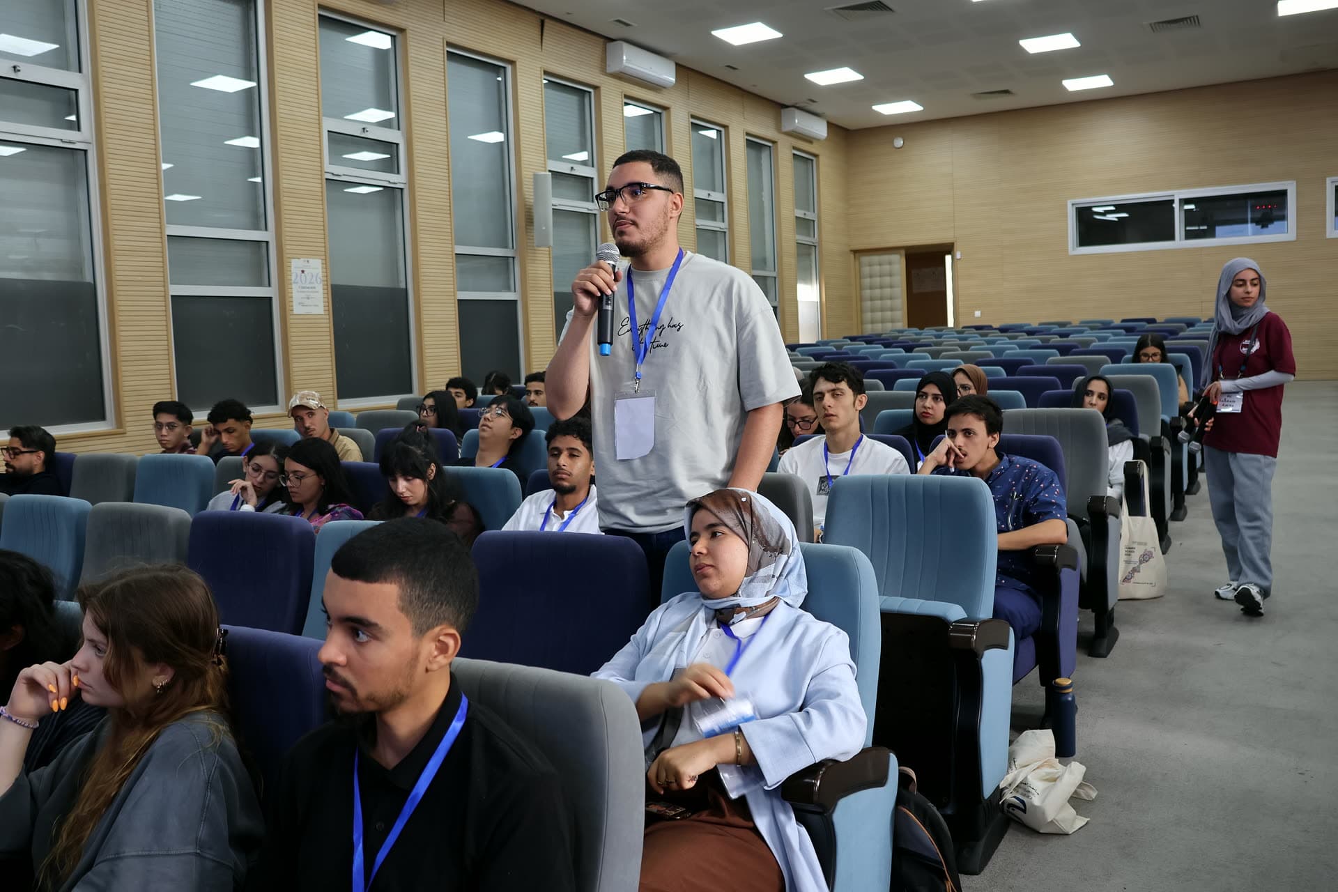 A participant standing among the rows to ask his question.
