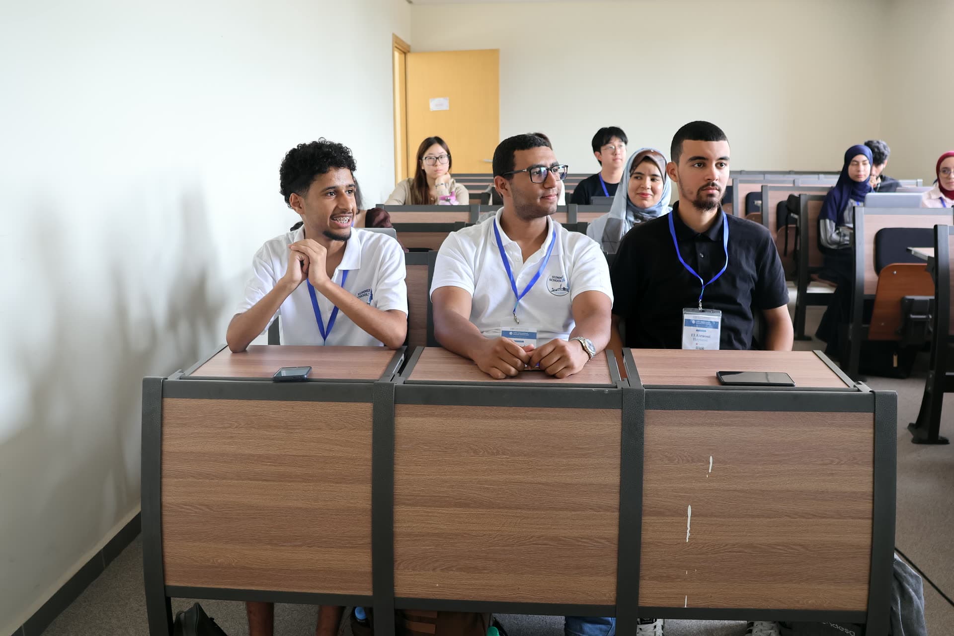 Three participants smiling at their classroom desks between exercises.