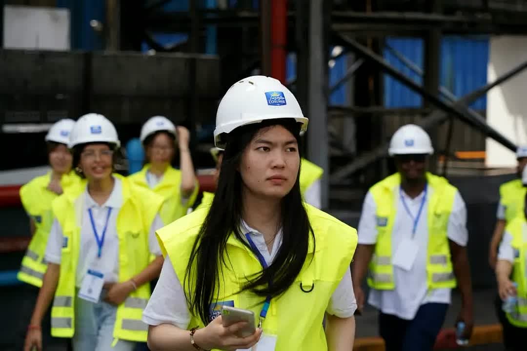Participants in white helmets and yellow vests walking through the Cosumar factory.