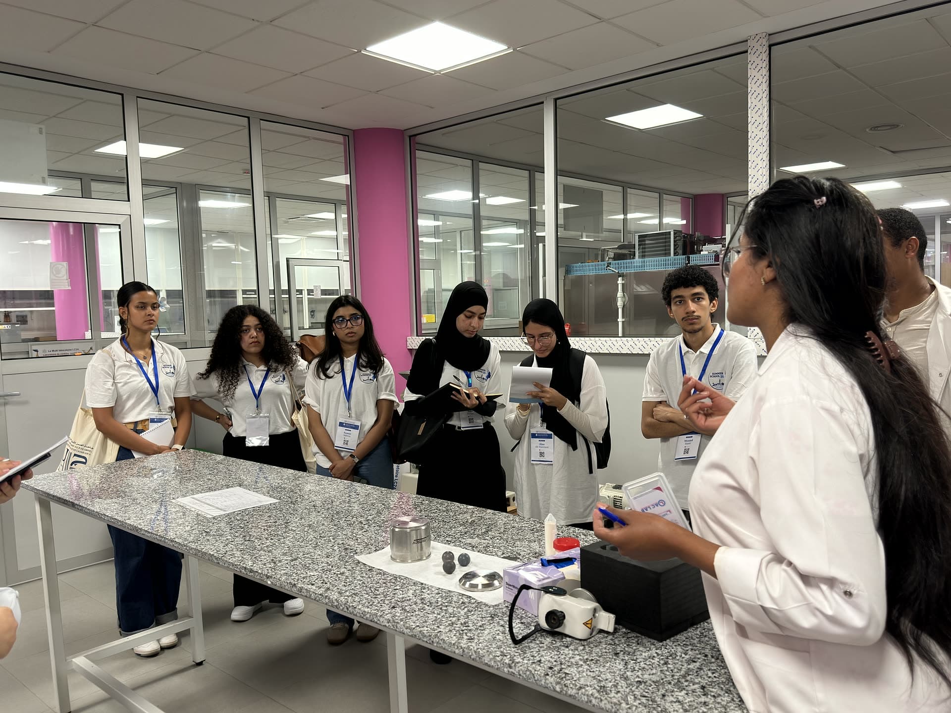Bench demonstration at LC2A — samples and a microscope, participants taking notes.