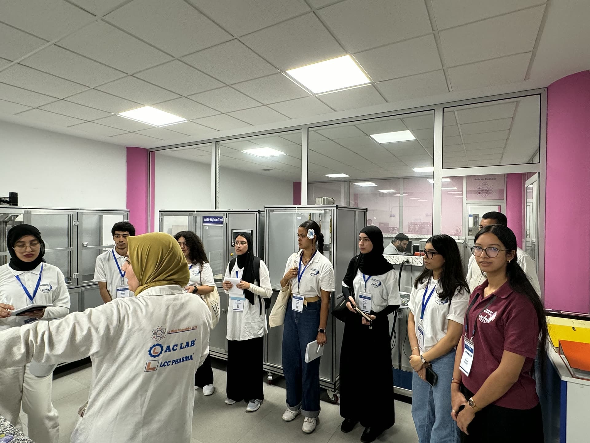 LC2A staff in white coats explaining the analysis line to visiting participants.