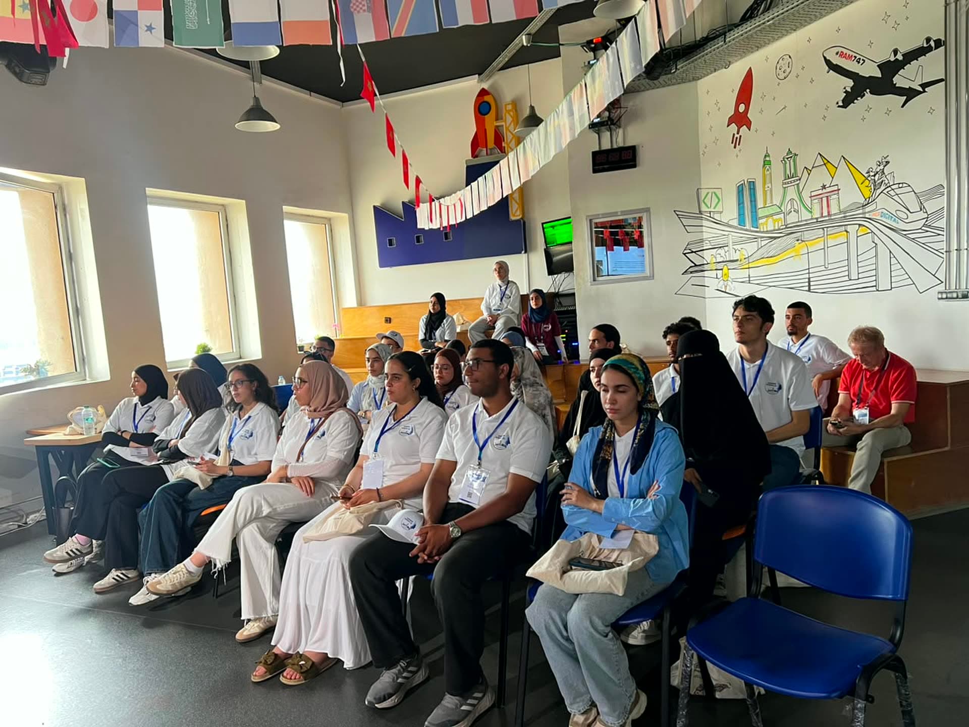 Participants seated under the wall of country flags at Technopark.