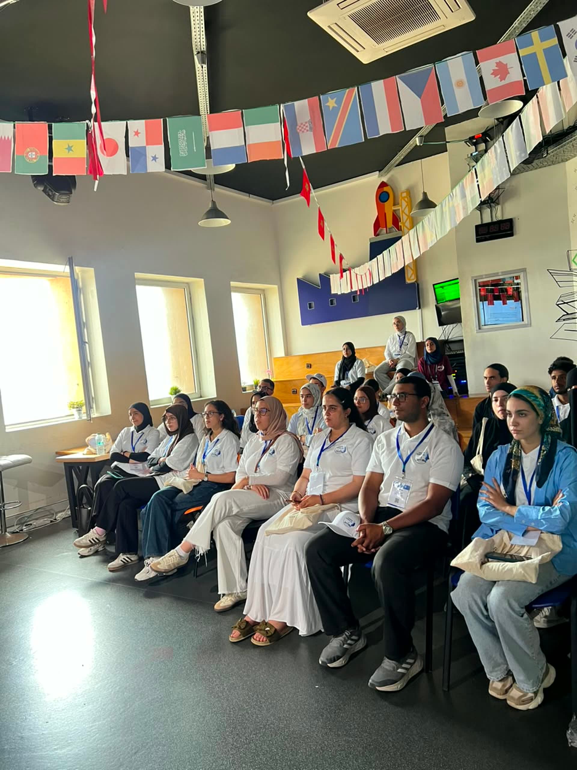 Rows of participants following the session under the flag garlands at Technopark.