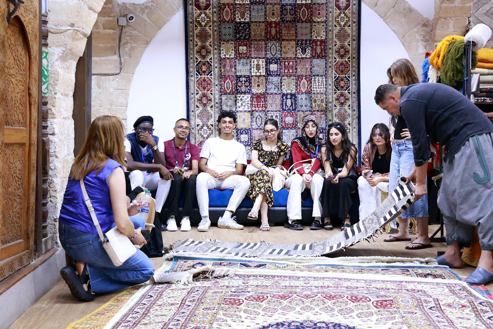 Participants seated beneath a wall of Moroccan carpets during the artisan demonstration.