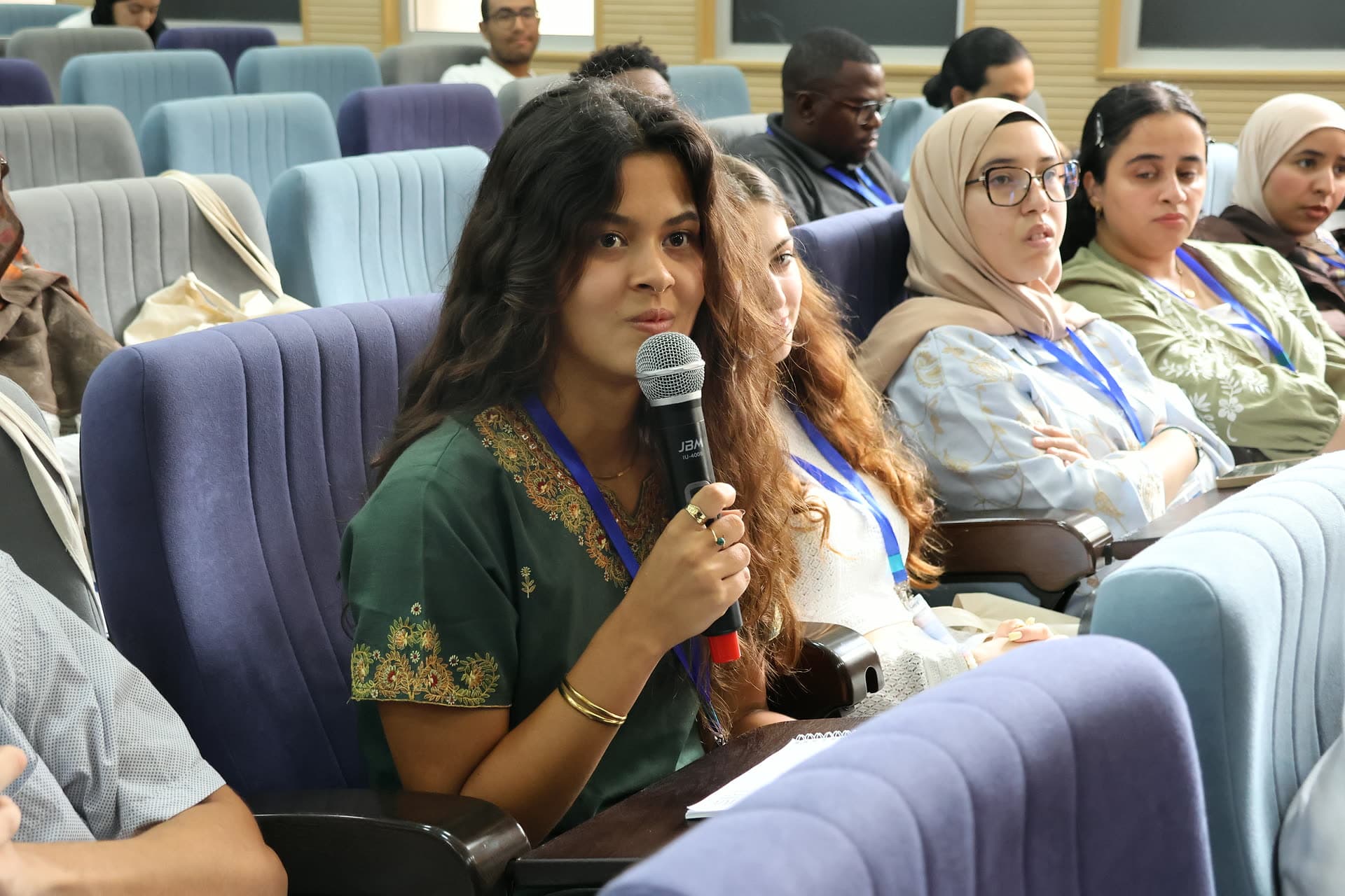 Participant asking a question into the microphone from her seat.