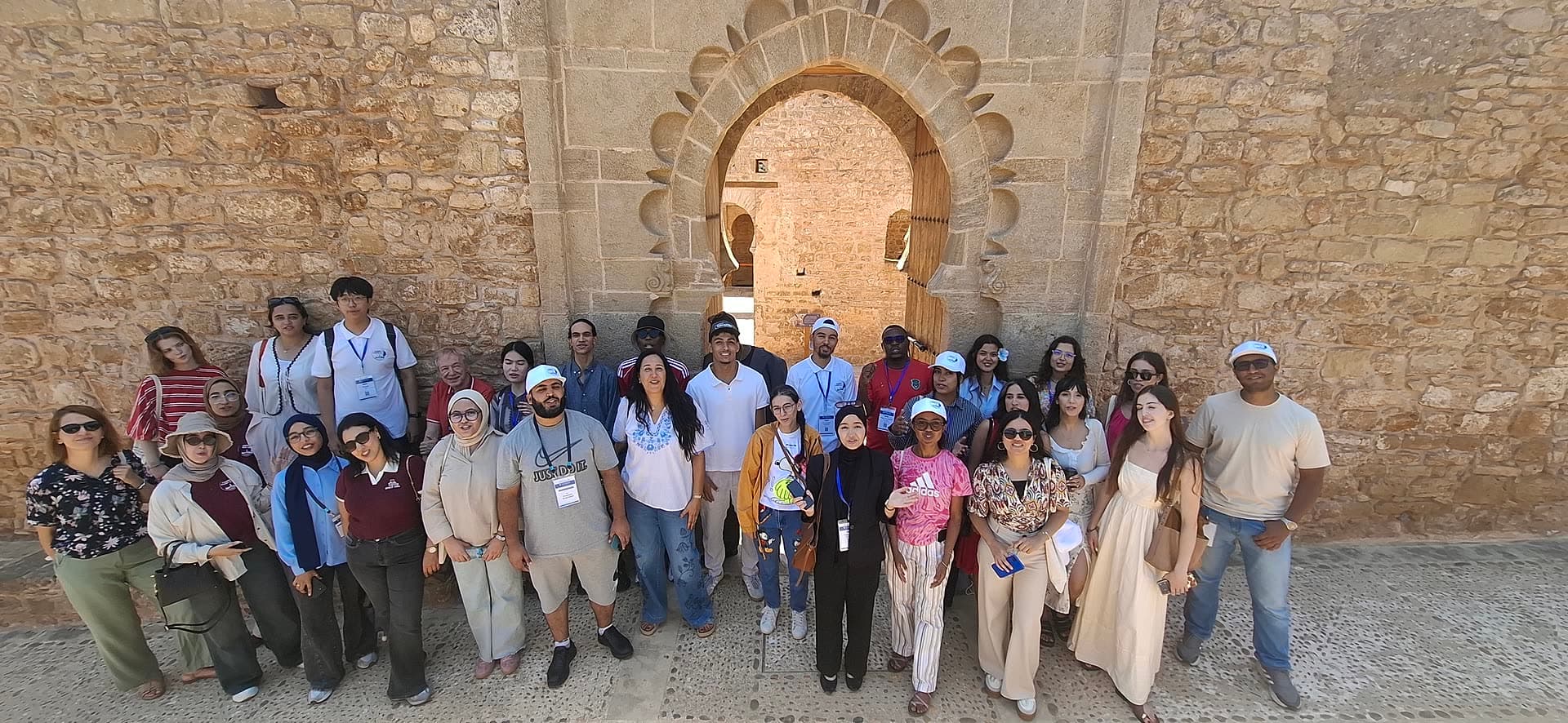 Group photo beneath the carved Almohad gate of the Chellah necropolis.