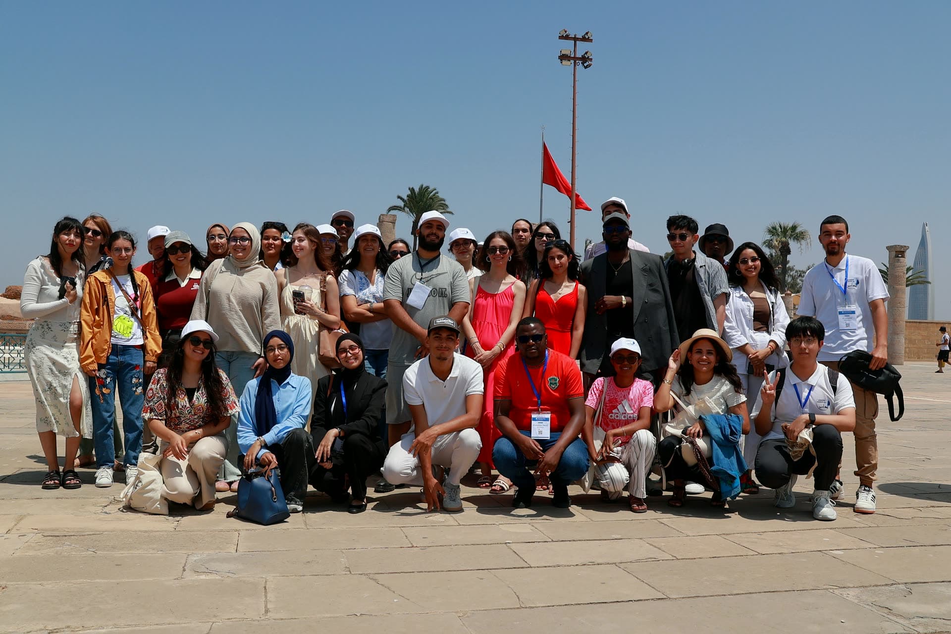 Big group photo on the Hassan Tower esplanade under the Moroccan flag.