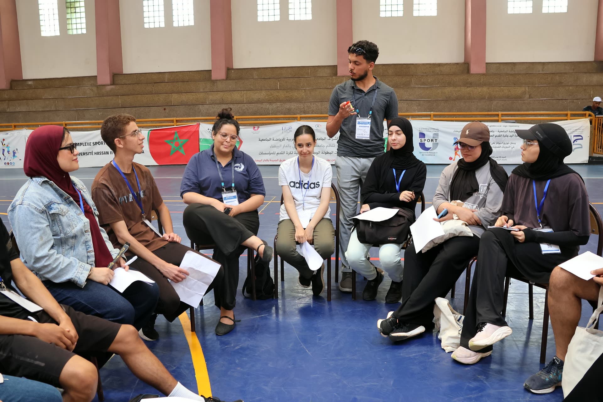 A participant standing to speak in the middle of a discussion circle in the gym.