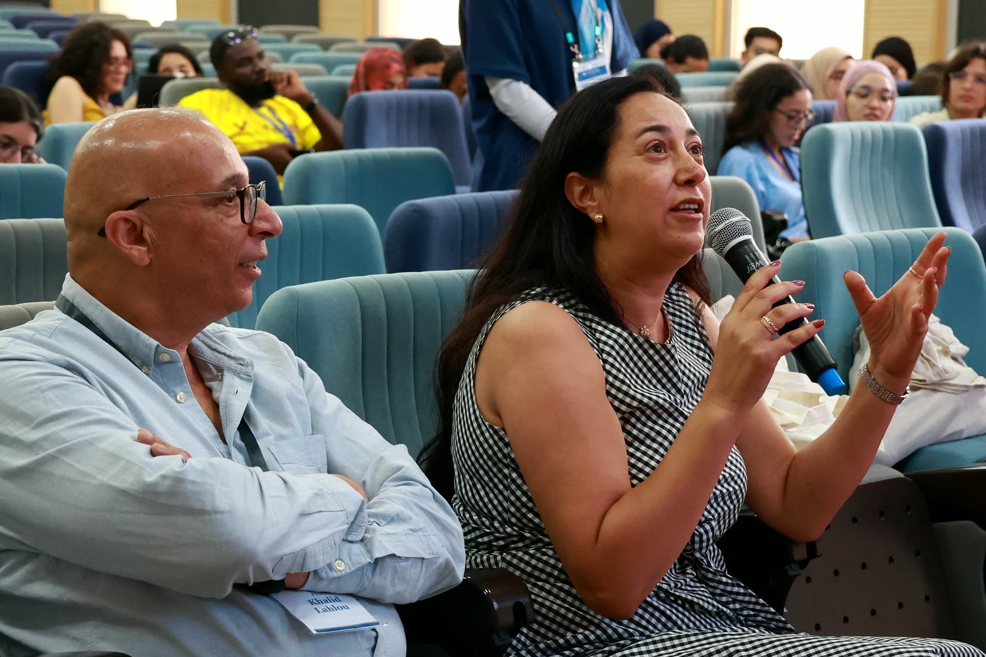 An animated question from the faculty row, microphone in hand.