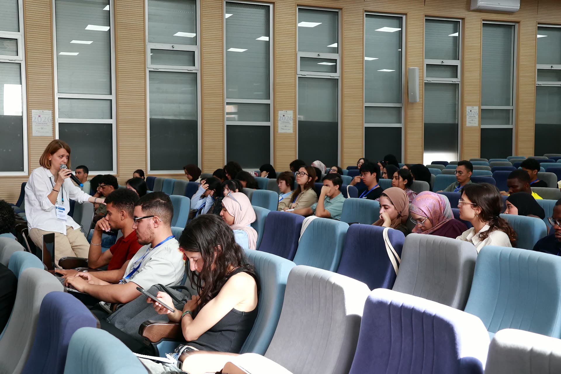 The lecturer walking among the auditorium rows with a microphone during an interactive session.