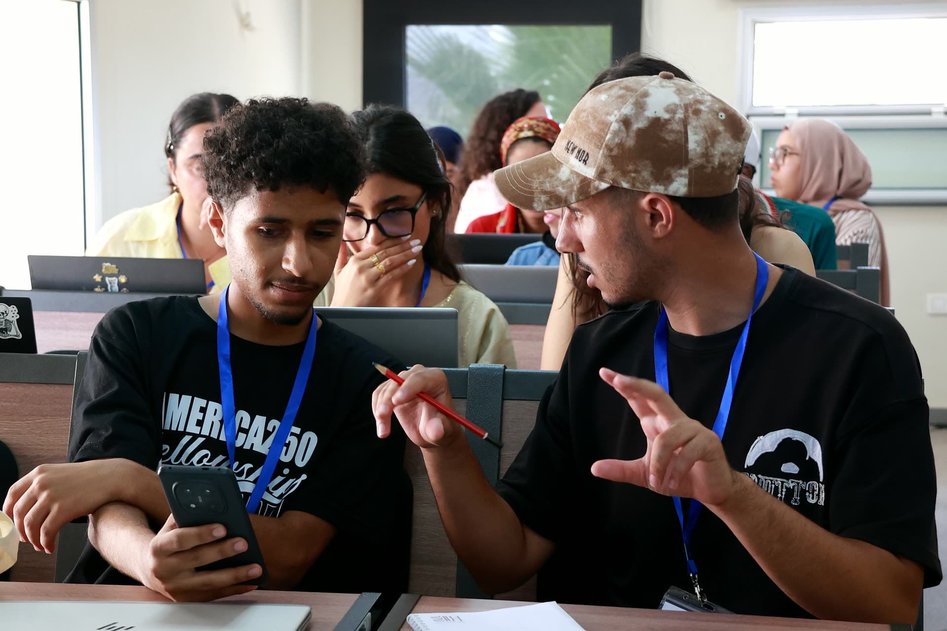 Two participants huddled over a phone, deep in discussion during a workshop.