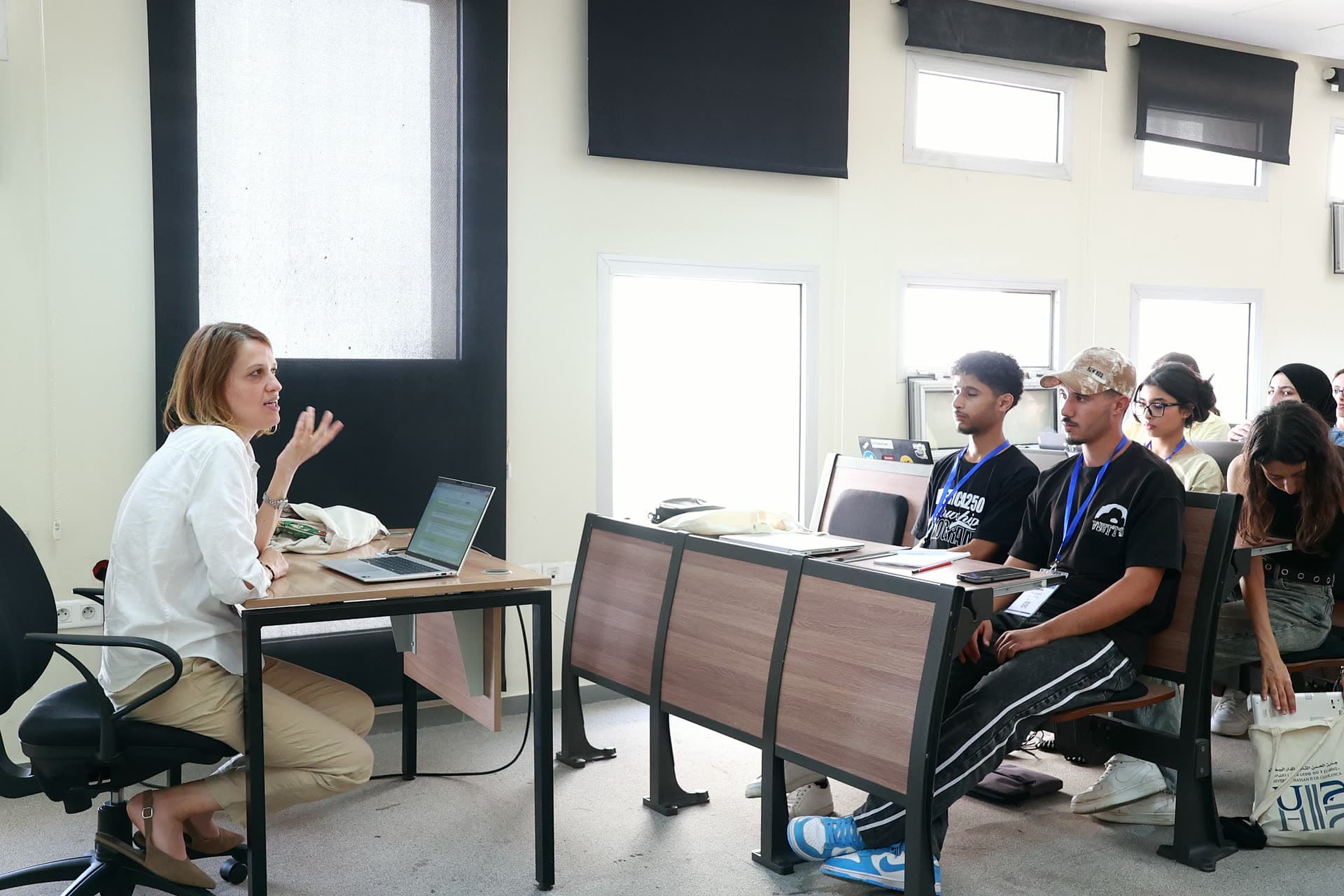 Workshop facilitator seated at her laptop in discussion with the class.