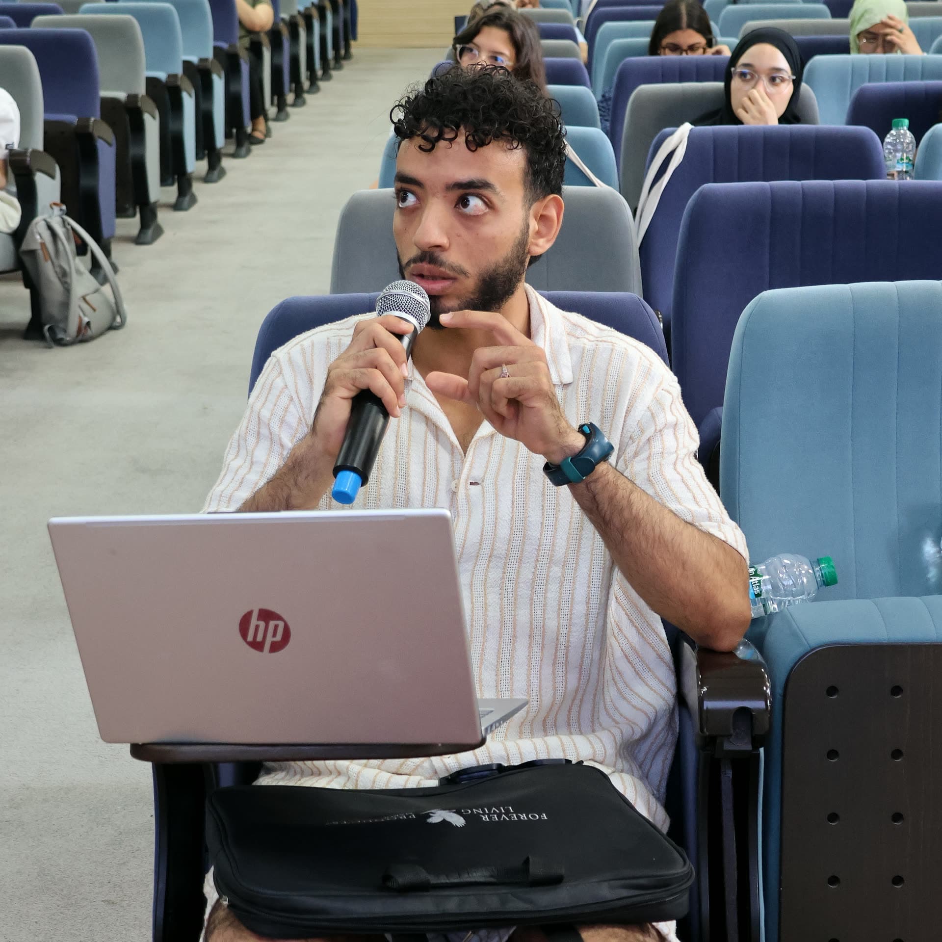 A participant balancing his laptop while making his point at the microphone.