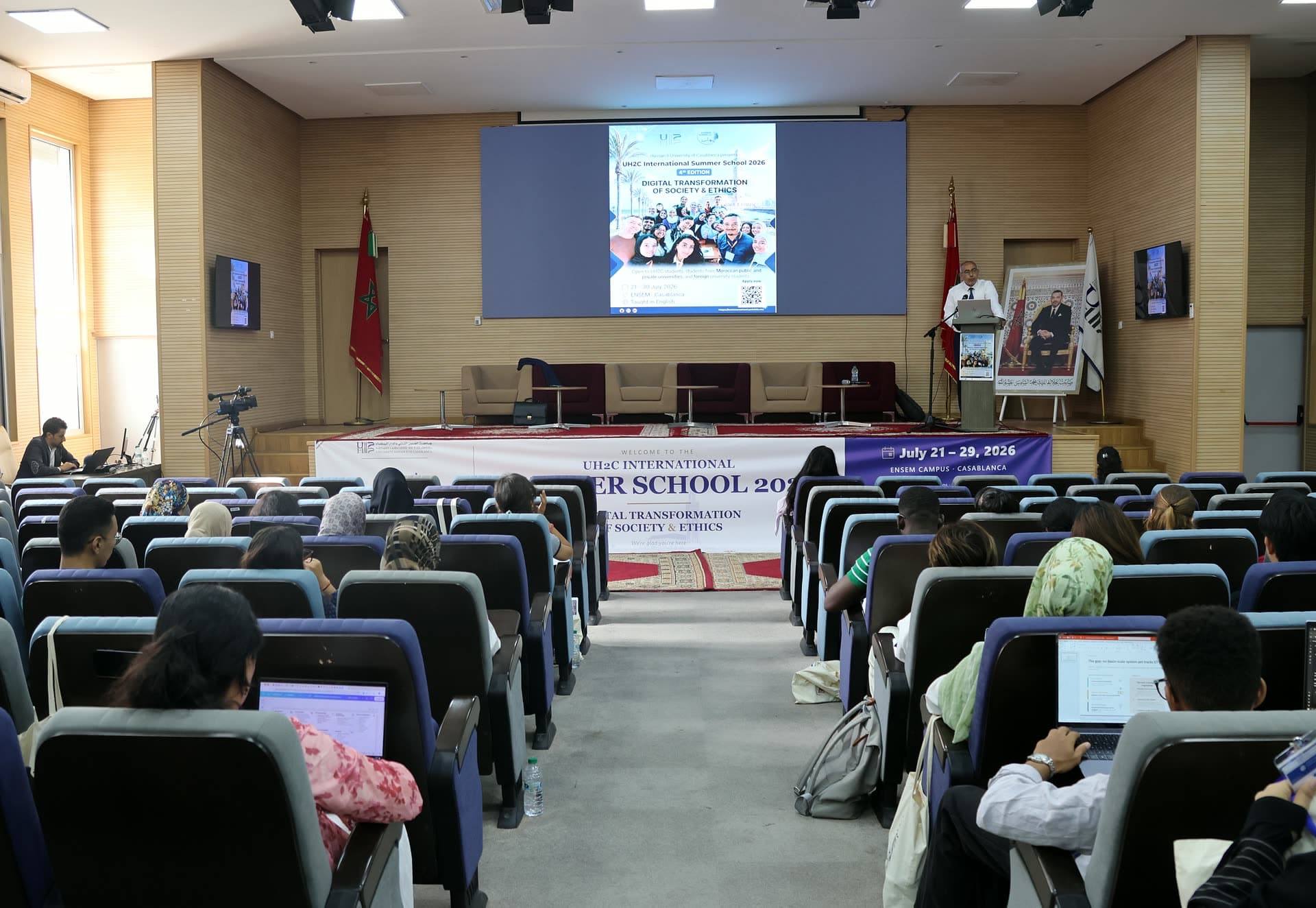 Auditorium wide view during the morning lectures, laptops open across the rows.