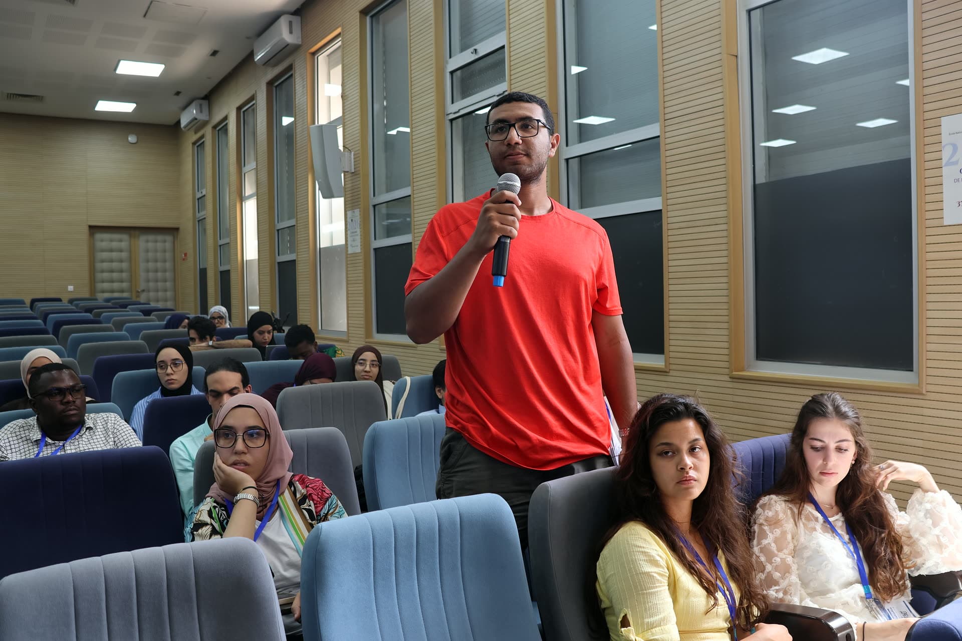 A participant in a red shirt standing to ask his question.