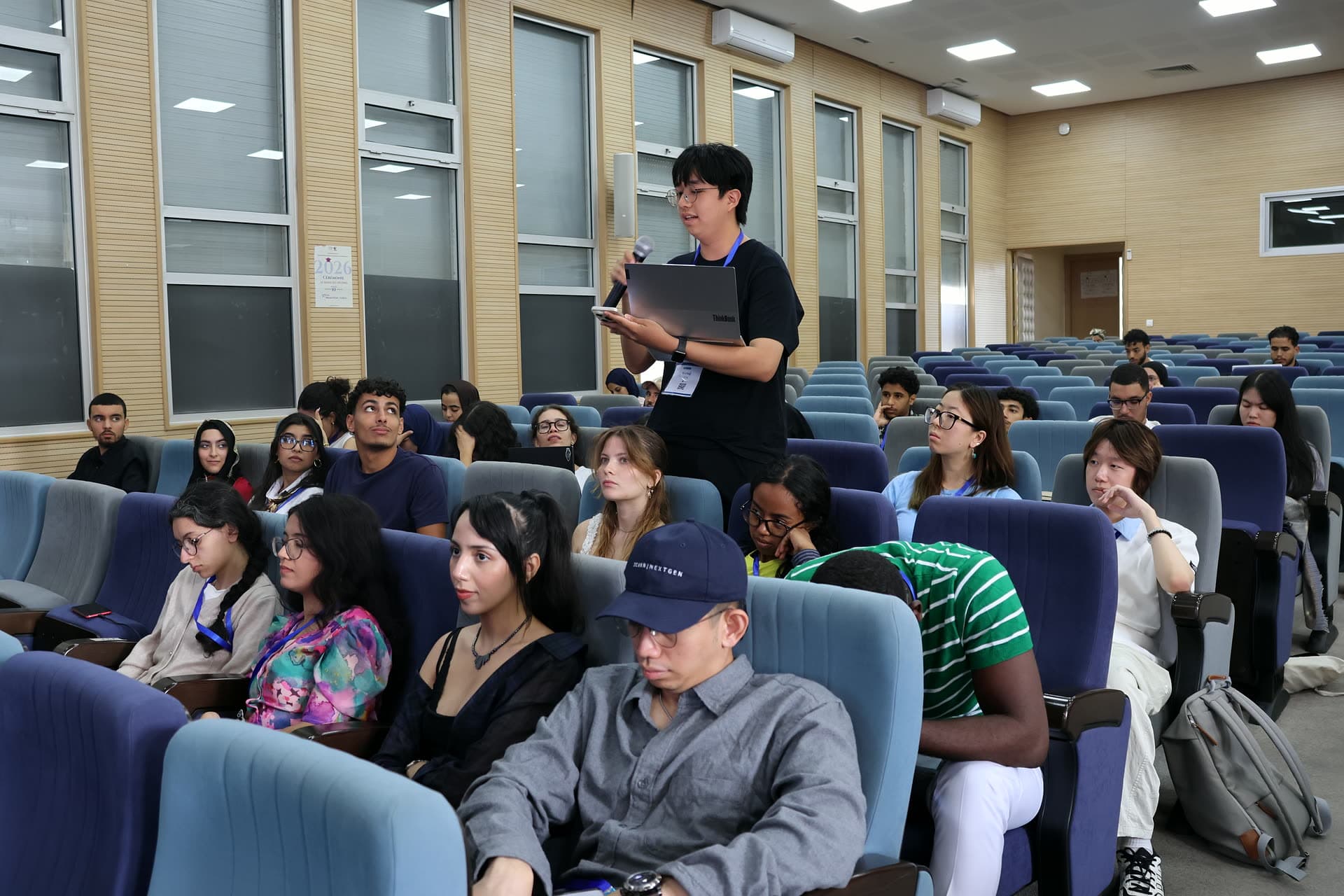 A participant standing among the rows reading from his laptop.