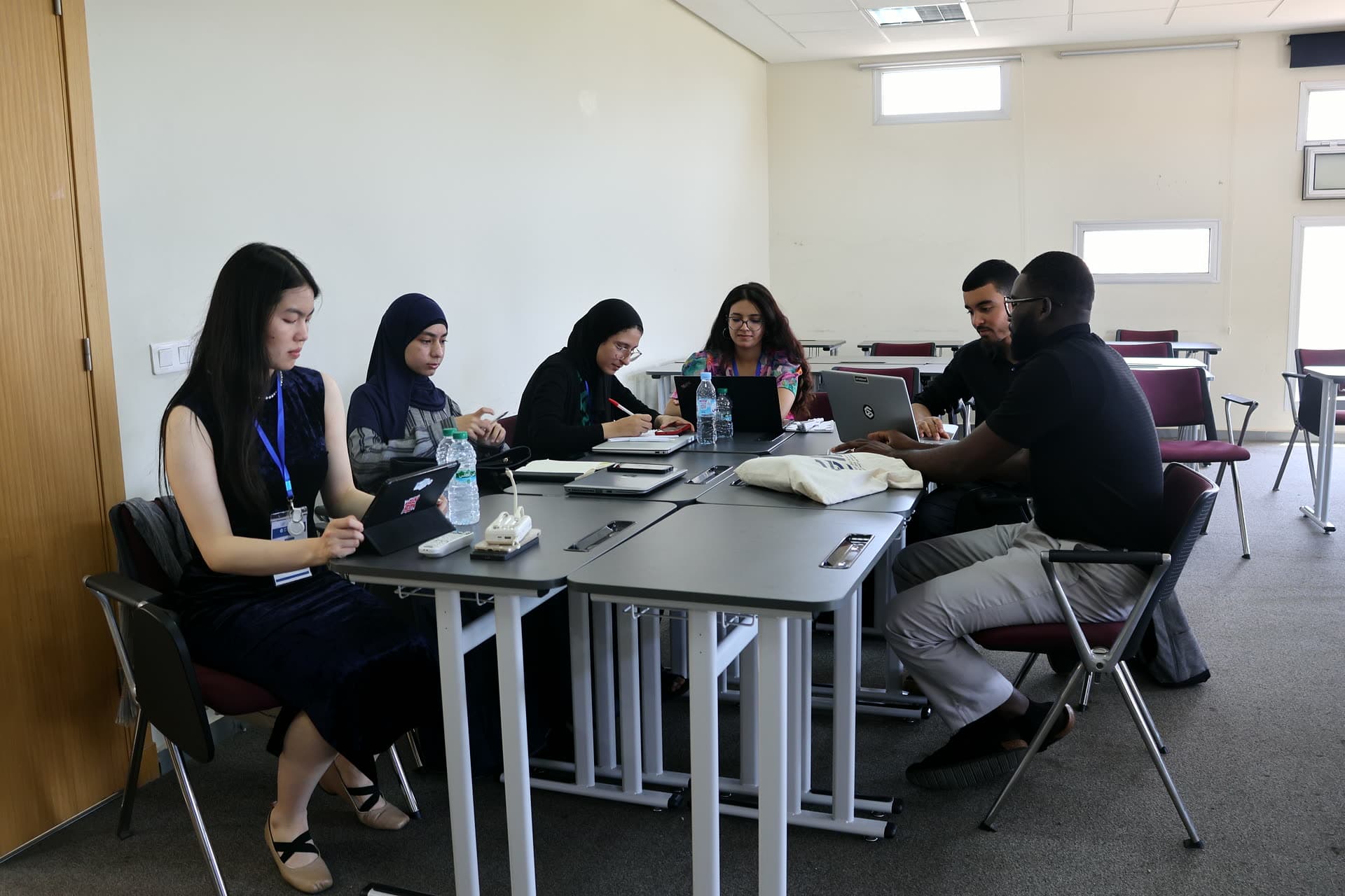 A team working together around the workshop table, laptops and notes out.