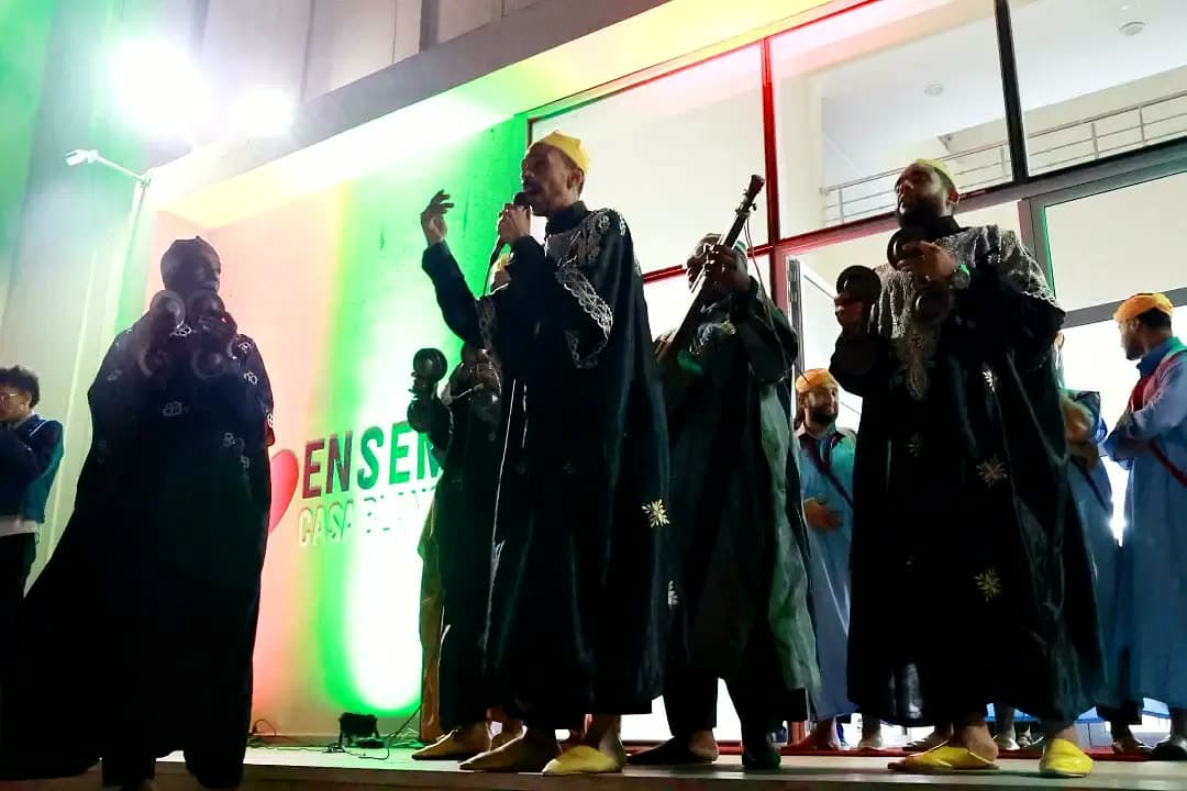Gnawa musicians performing at night beneath the ENSEM sign — powerful rhythms rooted in Moroccan tradition.