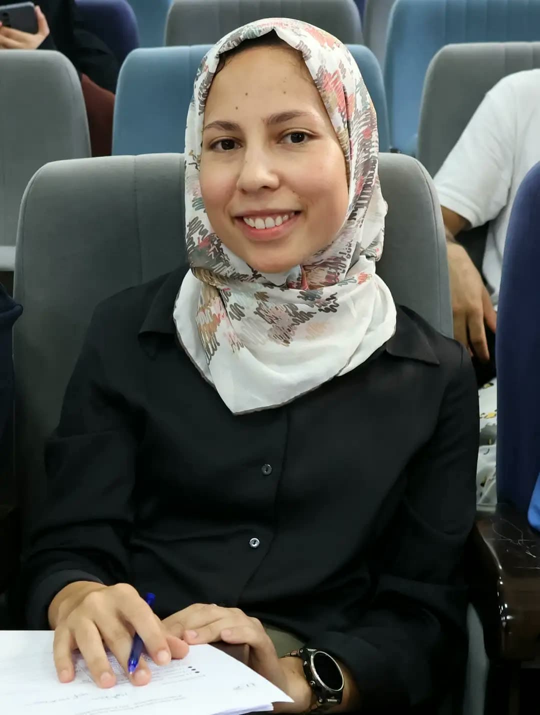 Jury member with her notes, smiling between presentations.